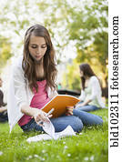 Caucasian woman studying in grass