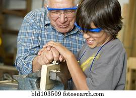 Hispanic grandfather and son planing wood in workshop