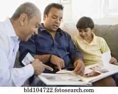 Hispanic grandfather, father and son looking at photo album