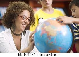 Hispanic teacher helping students with globe
