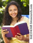 Mixed race woman reading book outdoors