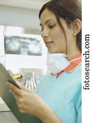 Indian female dental assistant writing on chart