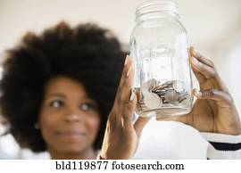 Mixed race woman holding jar of change