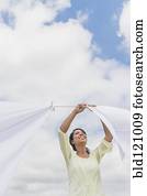 Black woman hanging sheets from clothesline