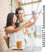 Couple taking self-portrait at sidewalk cafe