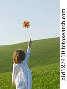 Girl holding up pinwheel in field