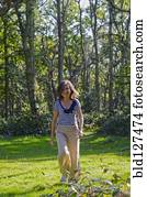 woman walking across clearing in forest