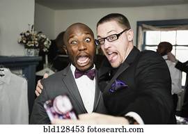 Groom and groomsman taking silly self-portrait