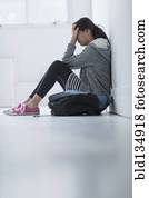 Mixed race teenage girl covering her face in school hallway