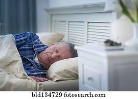 Senior Caucasian man sleeping in bed