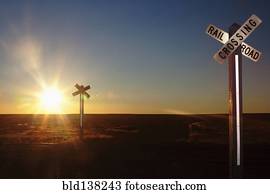 Railroad crossing sign on remote road at sunset