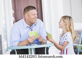 Caucasian father and daughter playing cards