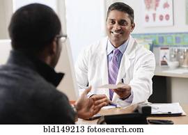 Doctor handing patient prescription in doctor's office