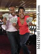 Excited couple holding cash winnings in casino