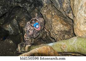 Caucasian climber exploring rock formation cave
