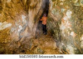 Caucasian woman exploring rock formation cave