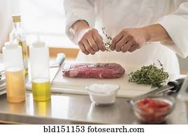 Korean chef seasoning meat in kitchen