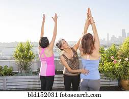 Teacher helping yoga students in class on urban rooftop