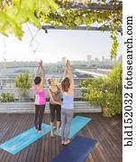Teacher helping yoga students in class on urban rooftop