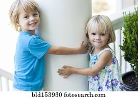 Caucasian children hugging column outdoors