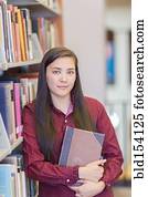 Mixed race student holding book in library Mixed race student holding book in library
