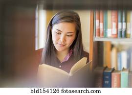 Mixed race student reading in library
