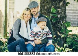 Caucasian family smiling under tree