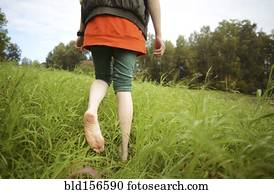 Close up of barefoot Caucasian woman walking in park