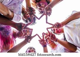 Low angle view of friends covered in pigment powder making star shape