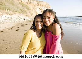 African American mother and daughter smiling on beach