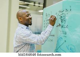 Black businessman writing on whiteboard