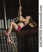 Caucasian athlete climbing rope in gym