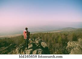 Caucasian hiker admiring view from remote rock formation