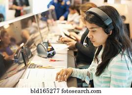 Hispanic student listening to headset at desk