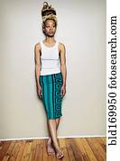 Black woman standing barefoot at wall