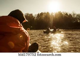 Caucasian fisherman sitting in canoe on river