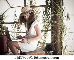 Woman using laptop in beach hut