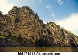 Distant boat on river near cliff