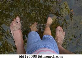 Father and daughter standing barefoot in water