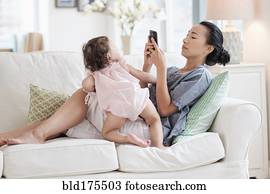 Mother photographing baby daughter