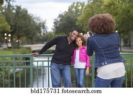 Mother photographing family on bridge