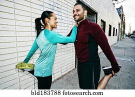 Athletic couple stretching on sidewalk