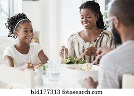 Black family eating salad at table