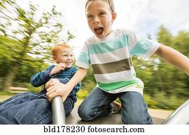 Caucasian boys playing on merry-go-round