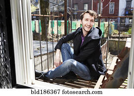 Caucasian man sitting on fire escape