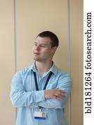 Caucasian man with Down Syndrome wearing badge at wall