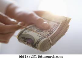 Hispanic woman holding rubber band around wad of cash