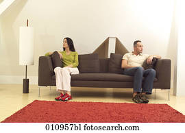 Couple sitting on sofa looking in different directions Couple sitting on sofa looking in different directions