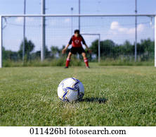 football lying on penalty spot with goalkeeper in background football lying on penalty spot with goalkeeper in background
