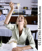 Lachende junge Frau, die Nudeln im Restaurant isst